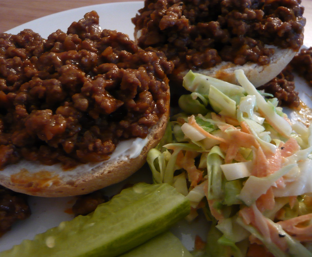 Sloppy joe lunch sandwiches with coleslaw and pickles on a plate