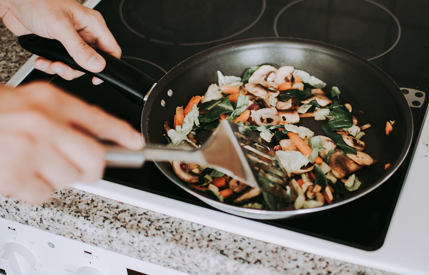 Vegetables cooking in a black frying pan on a stovetop for 30-minute dinner recipes for busy weeknights