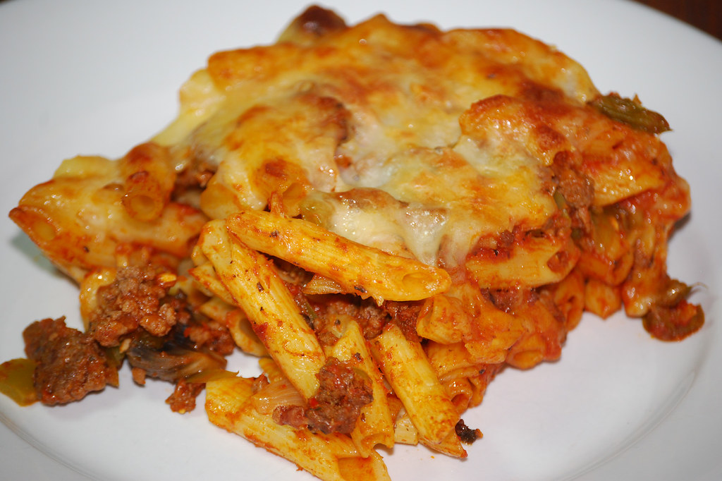 Ground beef pasta bake with melted cheese on a white plate