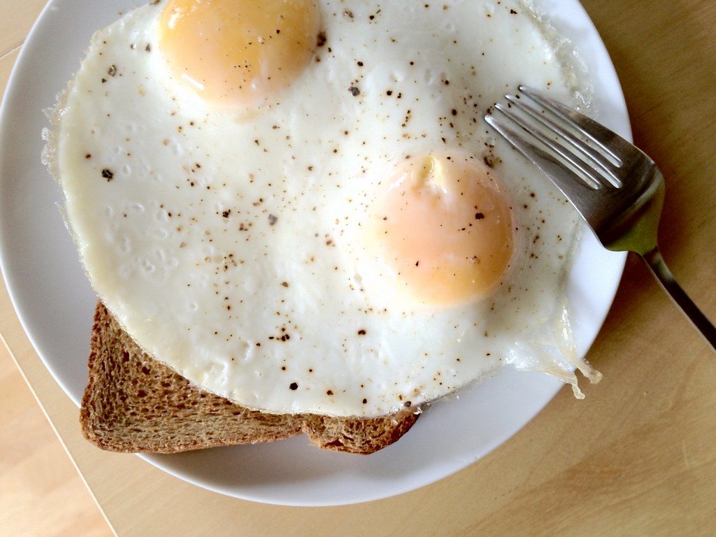 Fried eggs on a breakfast plate beside a fork