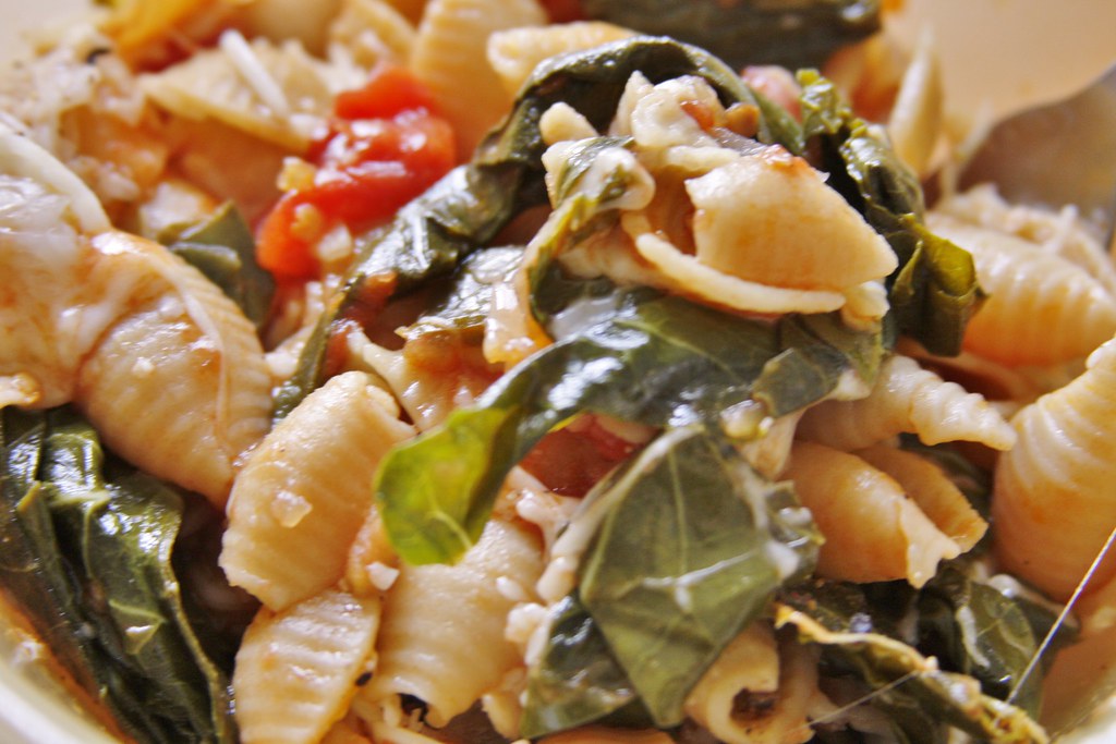 Close-up of shell pasta with greens and tomato sauce