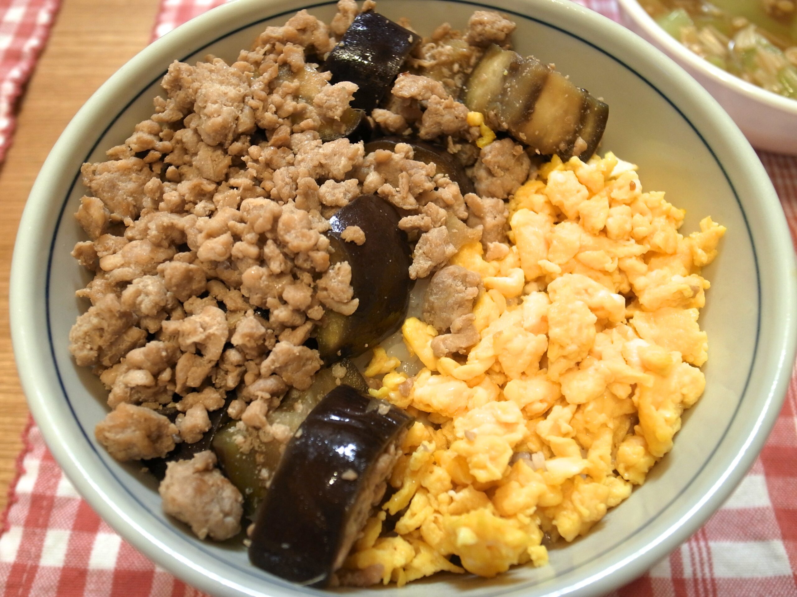 Rice bowl topped with egg, vegetables, and minced chicken