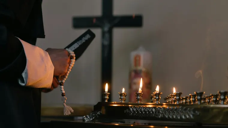 Altar com vela acesa e rosário em ambiente de oração