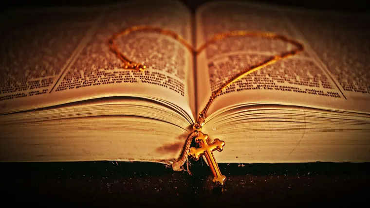 Pingente dourado em cruz sobre um livro
