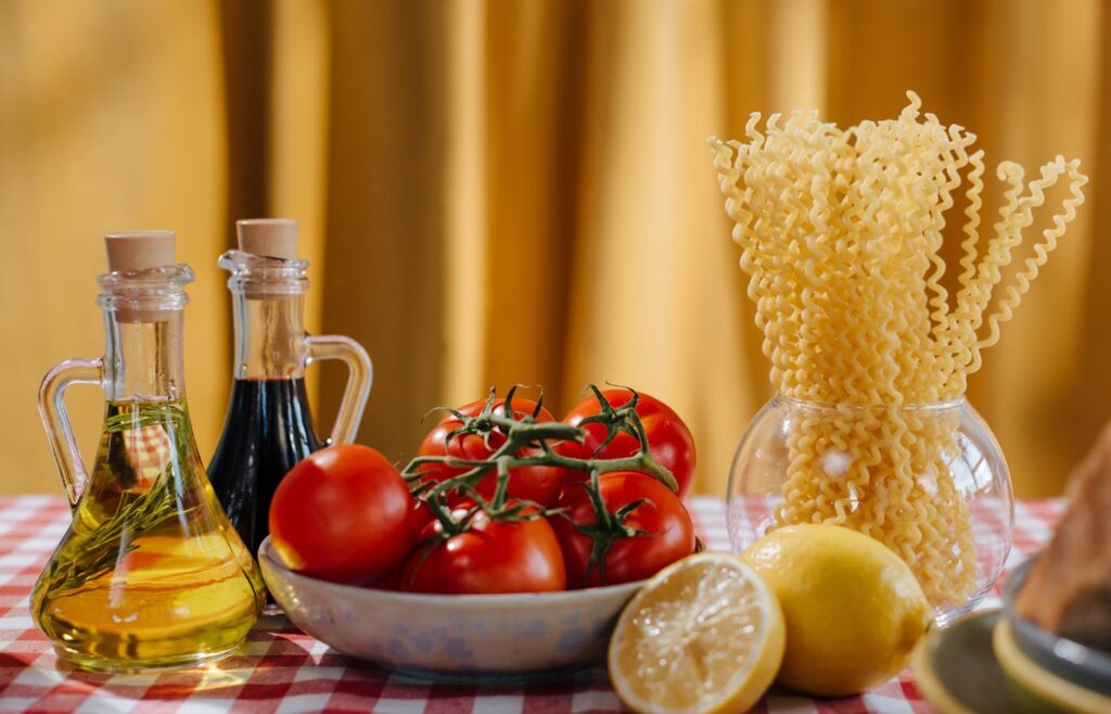 Pantry ingredients with pasta, tomatoes, oil, vinegar, and lemons