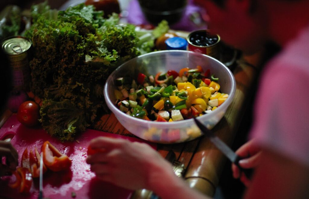 Person chopping vegetables beside canned pantry ingredients for a quick meal