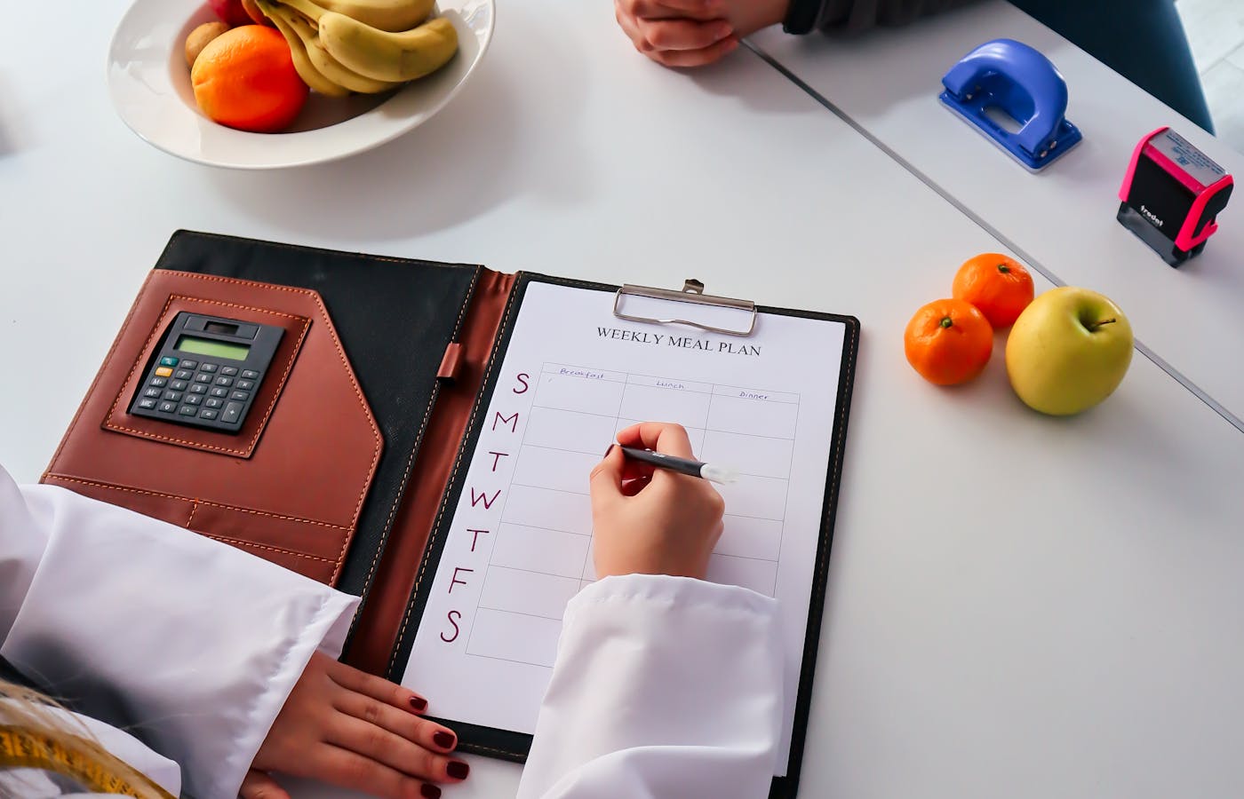 Weekly meal plan worksheet with fruit on a white table