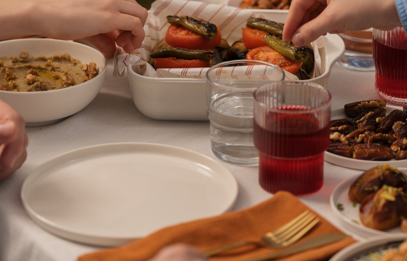 Hands serving roasted vegetables at a dinner table