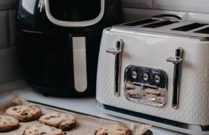 Black air fryer beside a white toaster on a kitchen counter