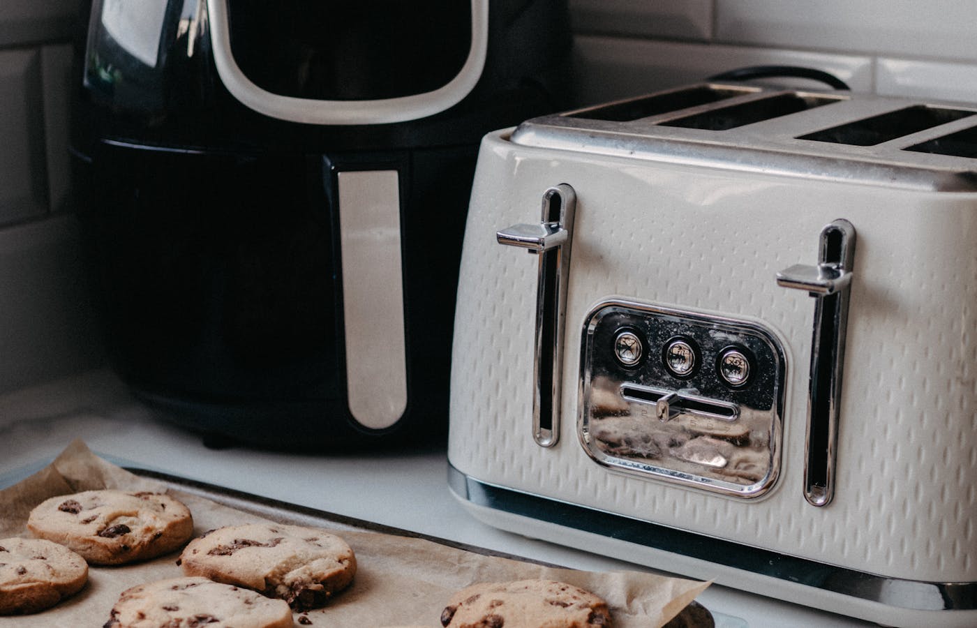 Black air fryer beside a white toaster on a kitchen counter