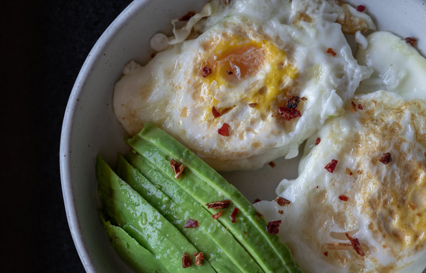 Breakfast bowl with fried eggs and sliced avocado