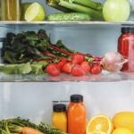 Fresh strawberries, beet greens, cucumber, celery, carrots, and citrus inside a refrigerator