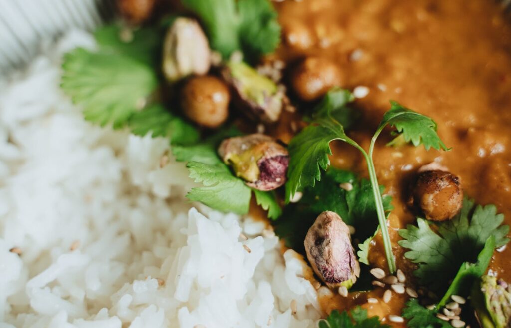 Meatless budget rice bowl with chickpea curry, cilantro, pistachios, and sesame seeds