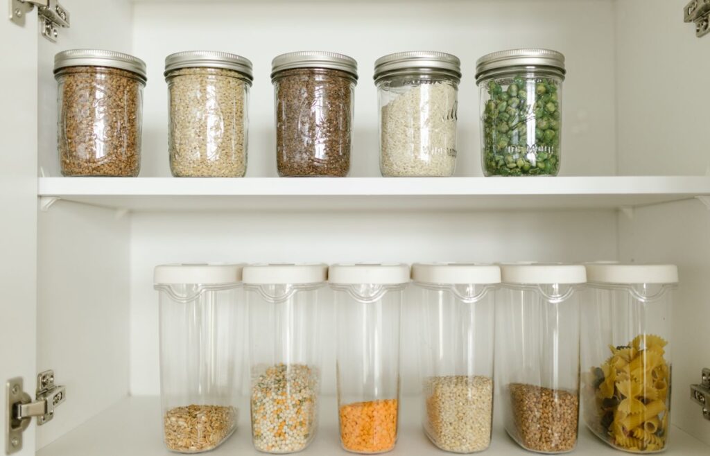 Kitchen cabinet shelf with jars of grains, lentils, rice, peas, and pasta