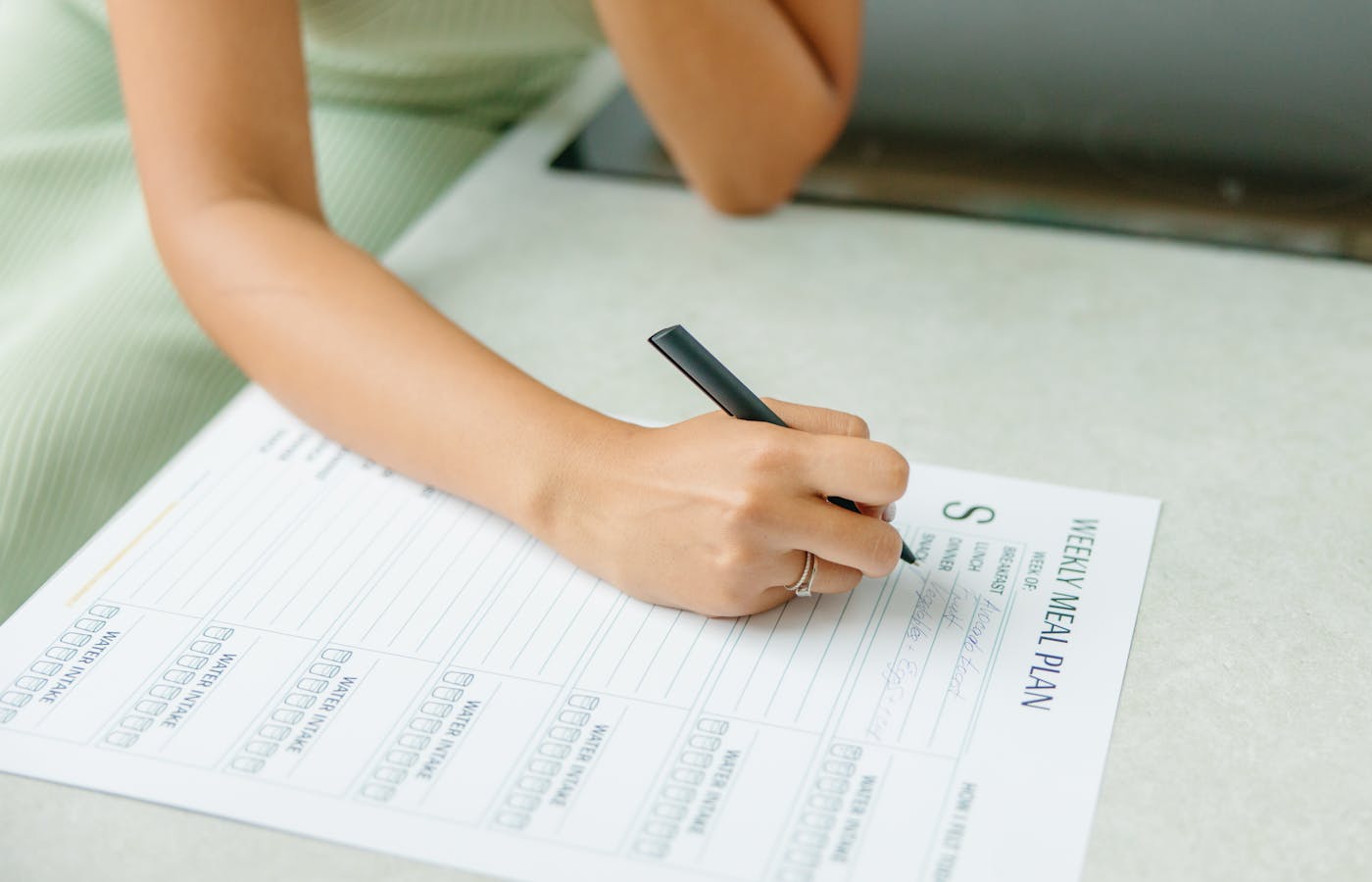 Hand writing on a weekly meal plan sheet