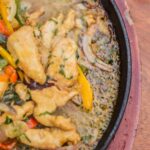 Chicken pieces cooking in a skillet with vegetables