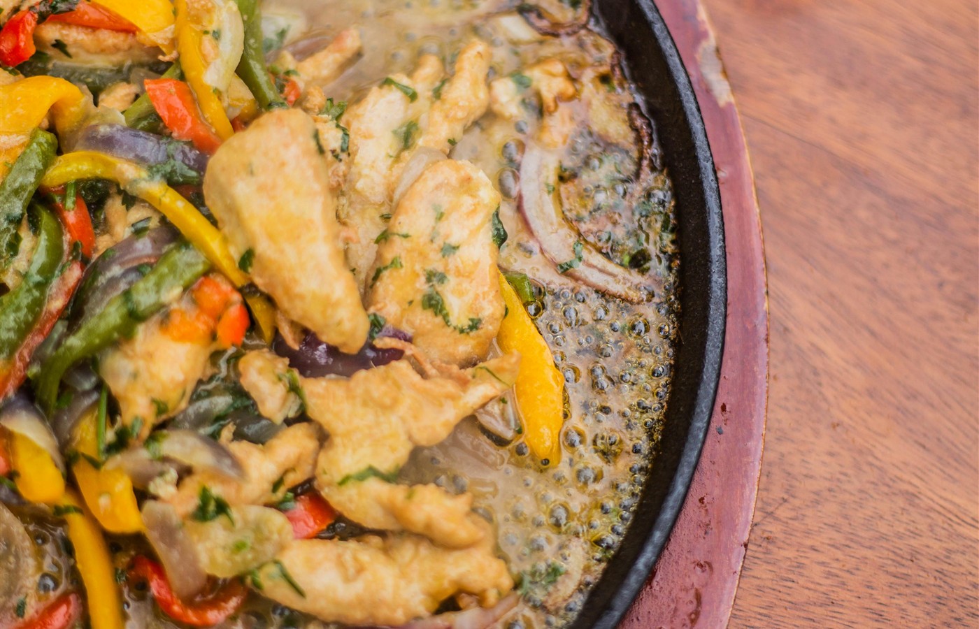 Chicken pieces cooking in a skillet with vegetables