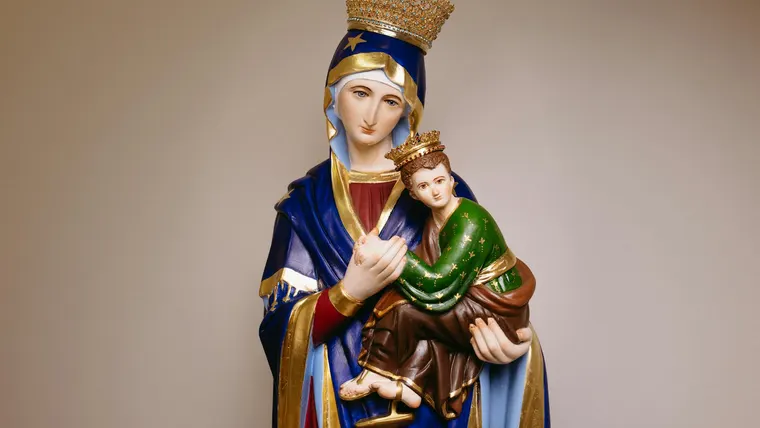 Estátua da Virgem Maria com o Menino Jesus, adornada com coroas, em contexto de devoção católica.