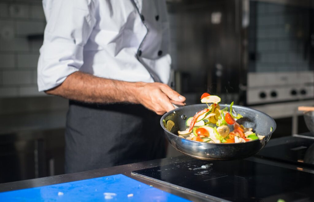 Vegetables being tossed in a hot skillet on a stovetop for quick pasta dinner ideas