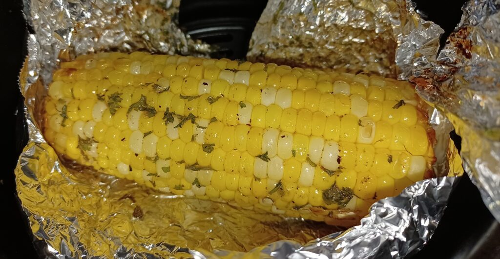 Corn on the cob inside an air fryer basket with foil