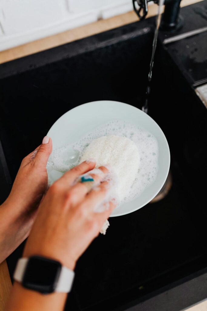 Hands washing a soapy plate in a kitchen sink