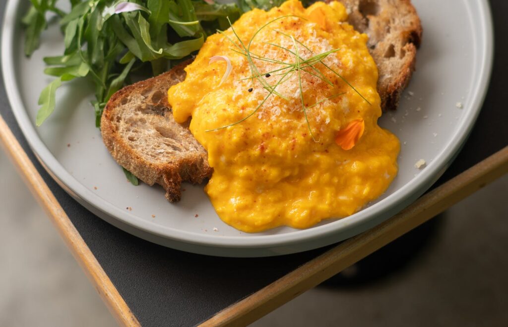 Scrambled eggs on toast with greens on a plate
