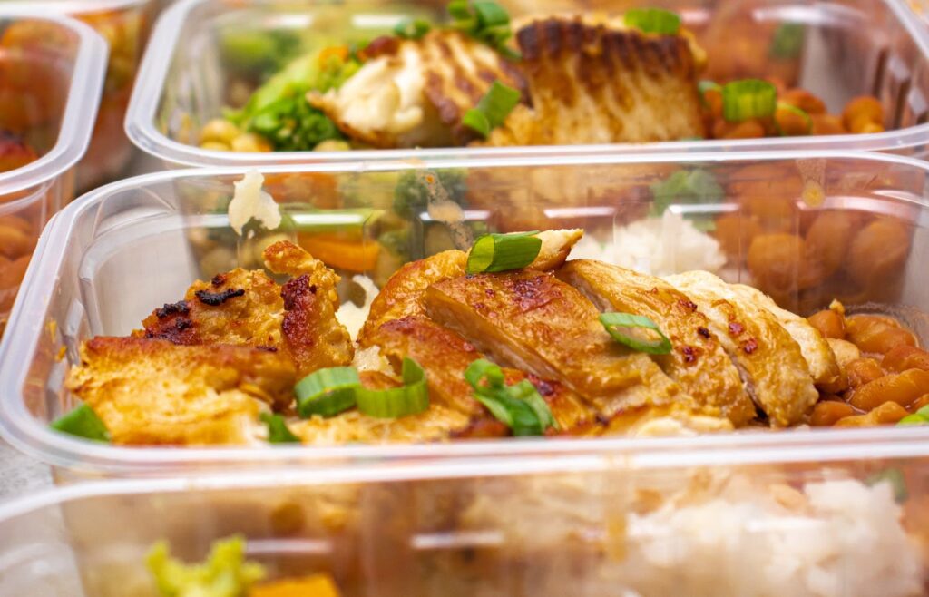 Meal prep containers with grilled chicken rice and vegetables