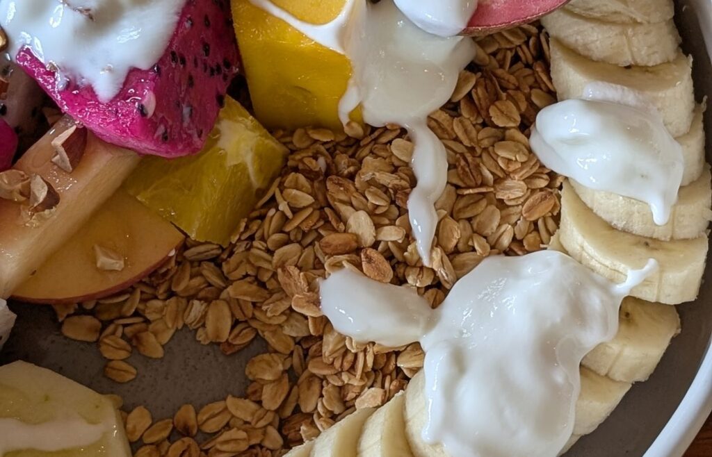 School morning fruit bowl with granola and yogurt on a table
