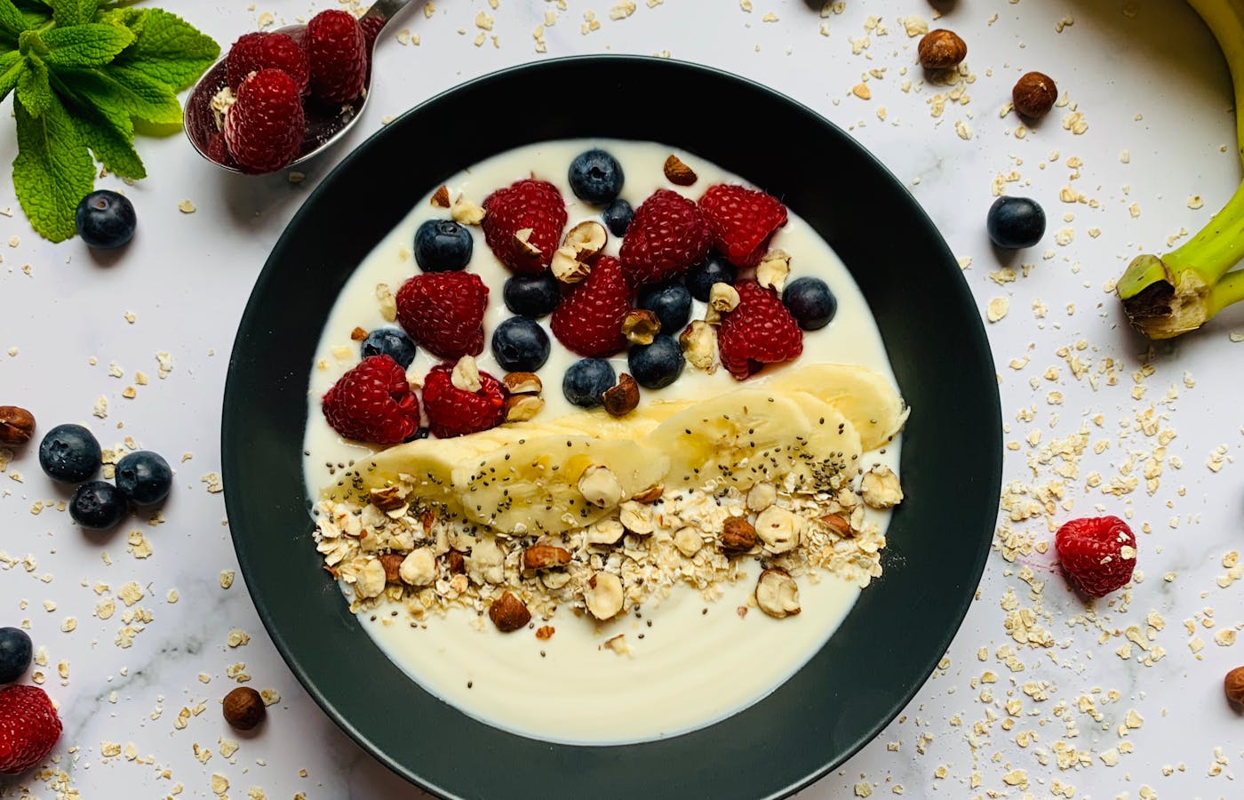 Oatmeal breakfast bowl with berries banana nuts and yogurt